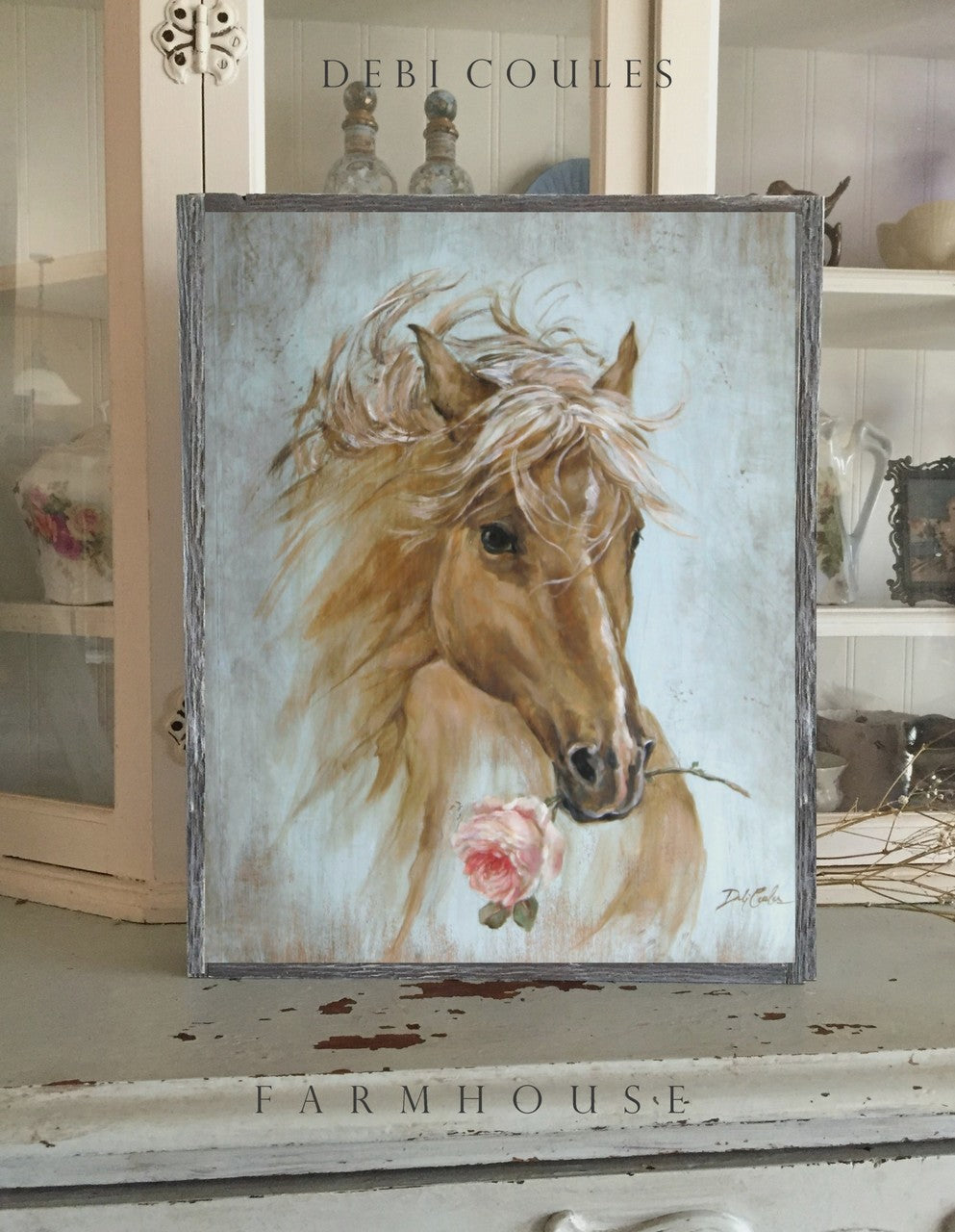 A Palimino stallion, golden mane flowing over a blue green distressed vintage background with a pink rose clutched in its mouth, framed in barn wood style frame, Debi Coules artist, Shabby chic, Cottage chic, farmhouse chic. 1.5 inch deep wall decor.