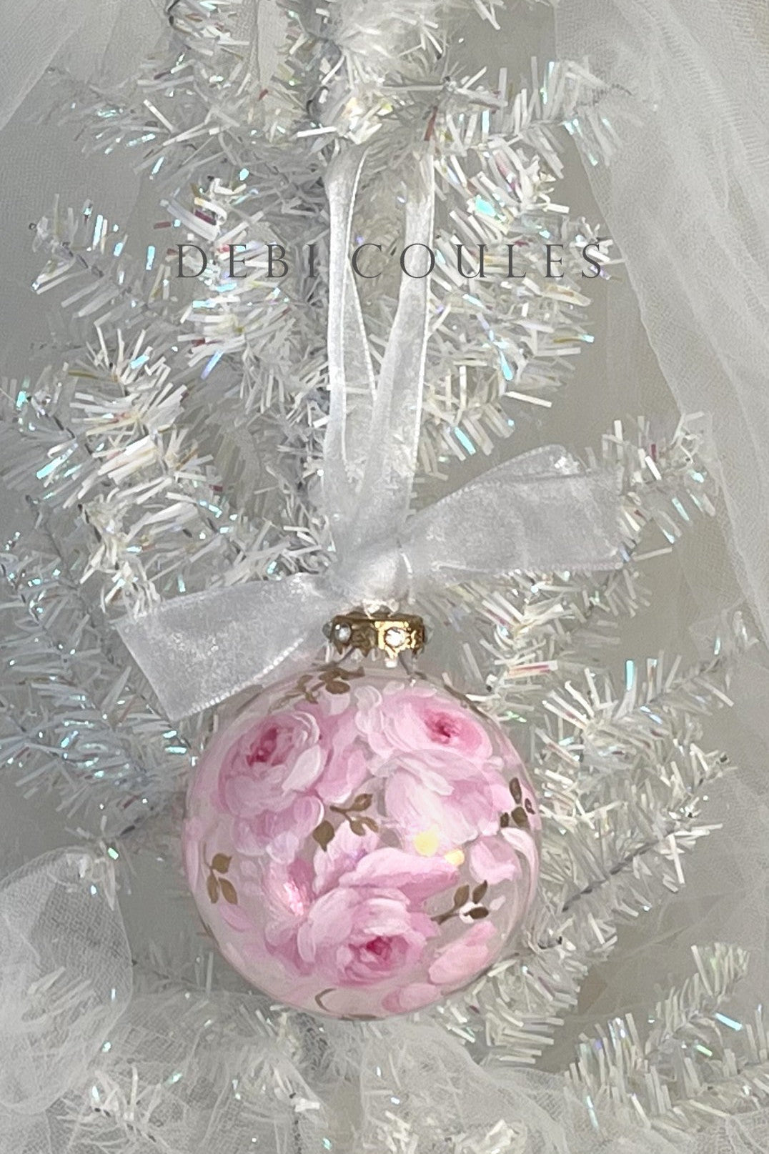 Decorative ornament with pink floral design on a white tinsel background