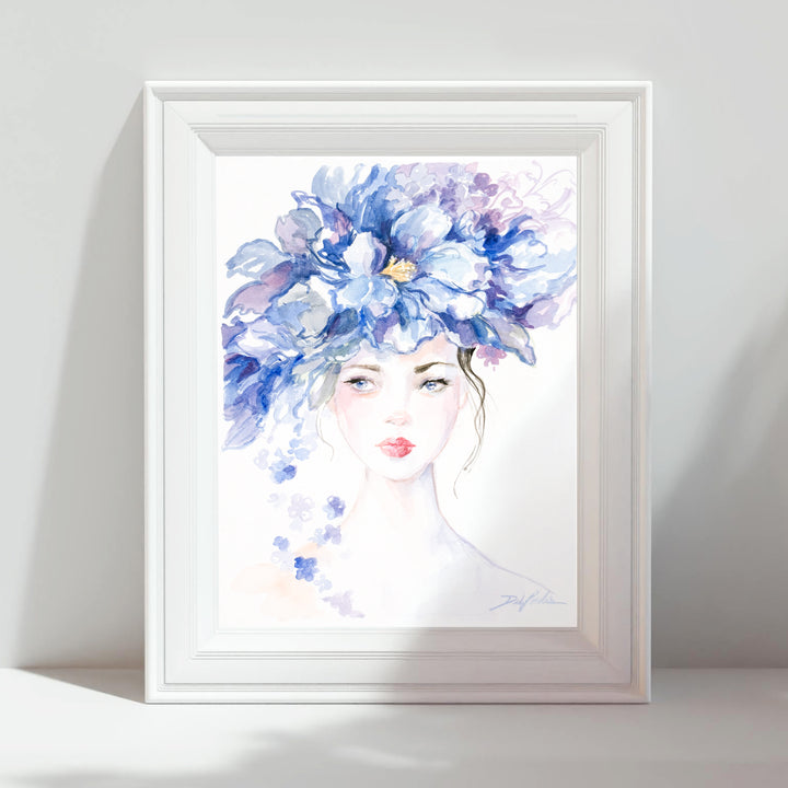 Framed artwork of a woman's face with a large blue floral headpiece on a white background