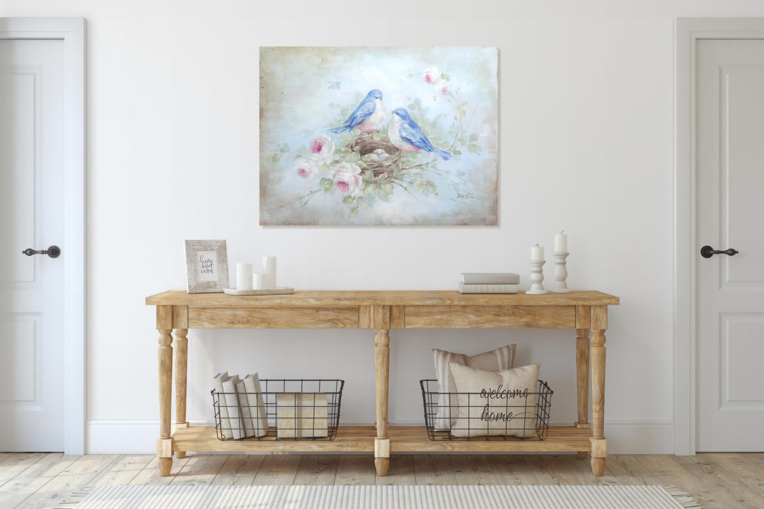 A canvas print of two bluebirds nesting among blooming roses. The print hangs in a hallway above a wooden entry table.