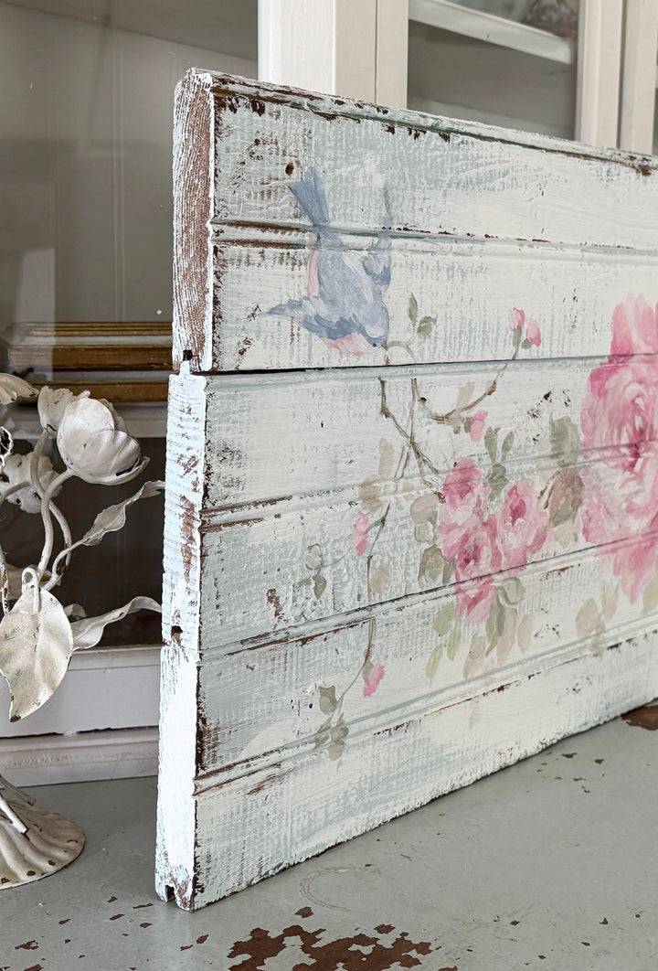 Side view of original hand-painted antique beadboard featuring romantic pink roses and bluebirds by Debi Coules, showing the reclaimed wood texture and depth.
