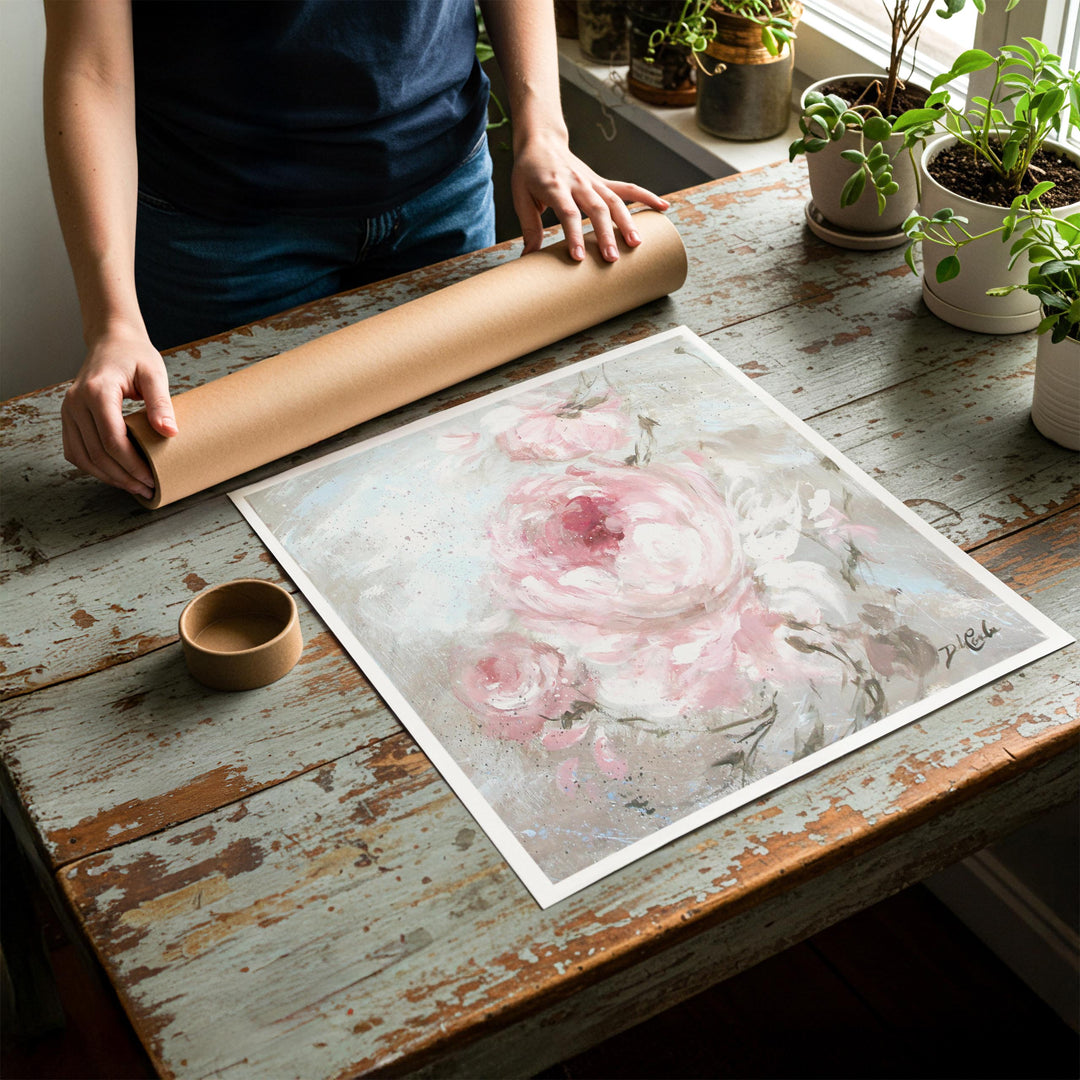 Person rolling up an unstretched canvas print of shabby chic rose artwork to be placed in a cardboard mailing tube