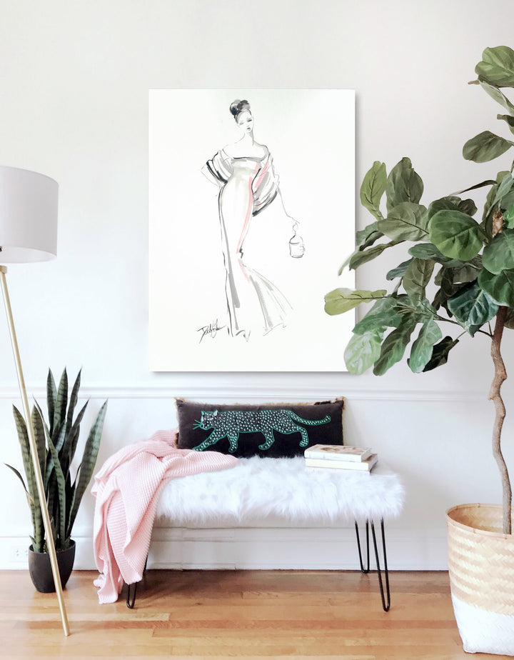 Canvas print of a fashion watercolor painting featuring a French model in a haute couture gown folding a birdcage handbag. The print hangs in an entry room above a faux-fur seating area.