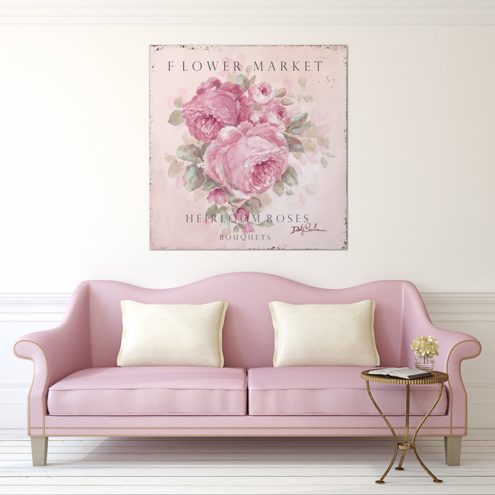 A large cottage sign of pink heirloom roses hangs above a vintage pink couch.