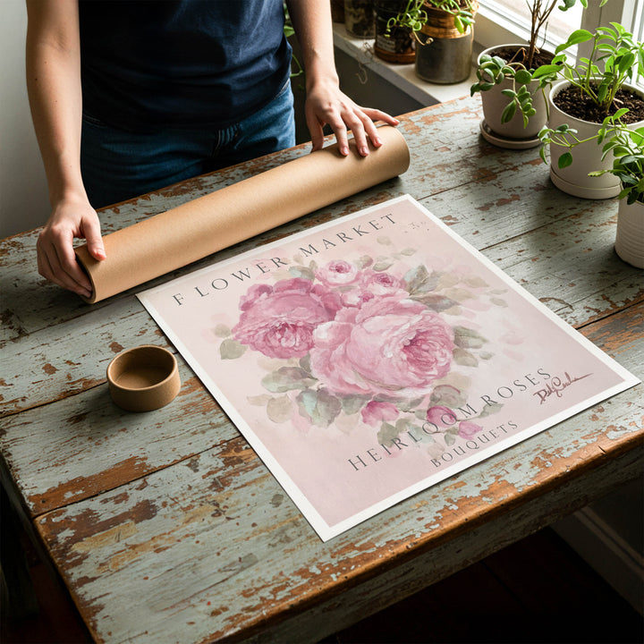 Person rolling up a fine-art paper print of a shabby chic cottage sign advertising heirloom roses to be placed in a cardboard mailing tube.