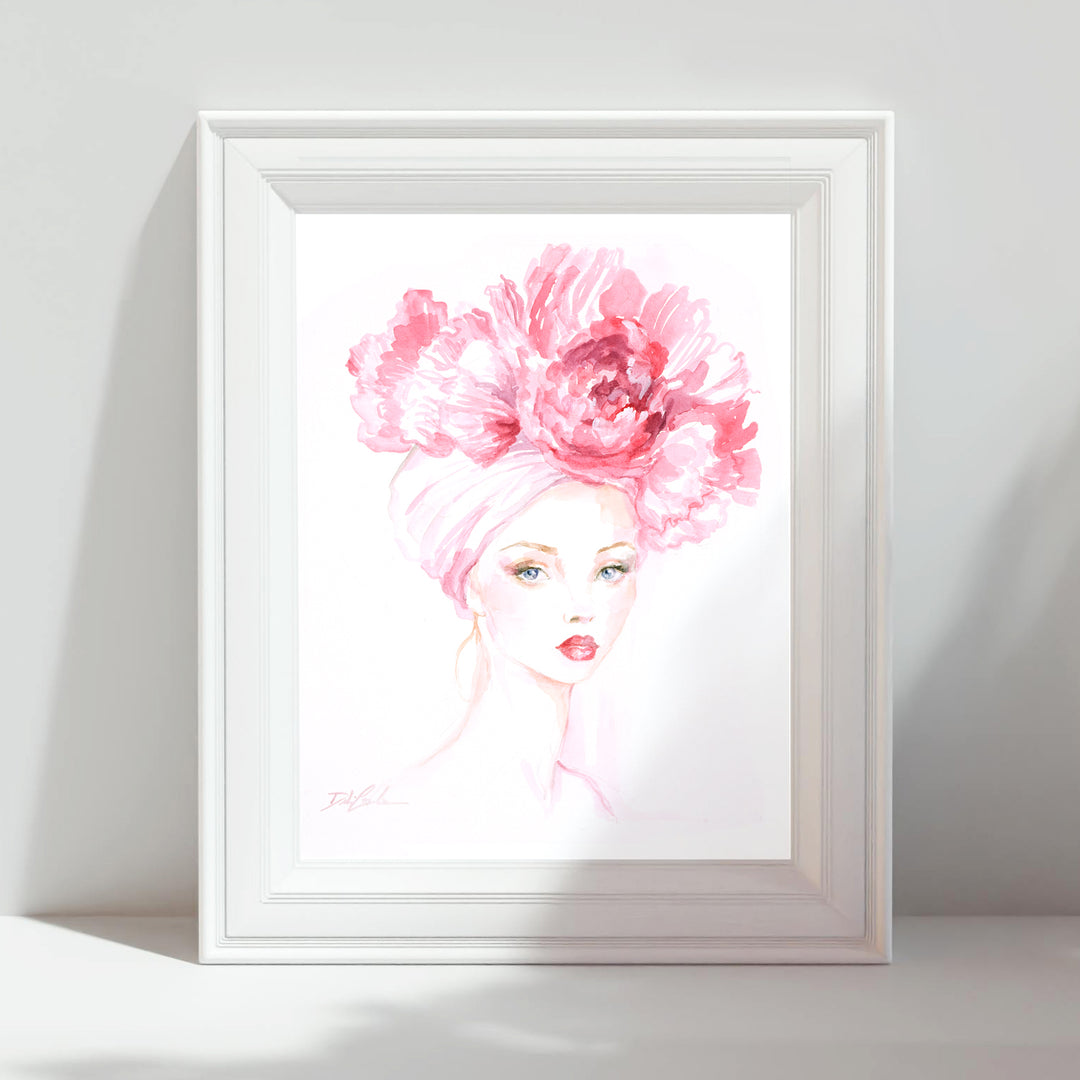 Framed artwork of a woman with a large pink flower on her head against a white wall.