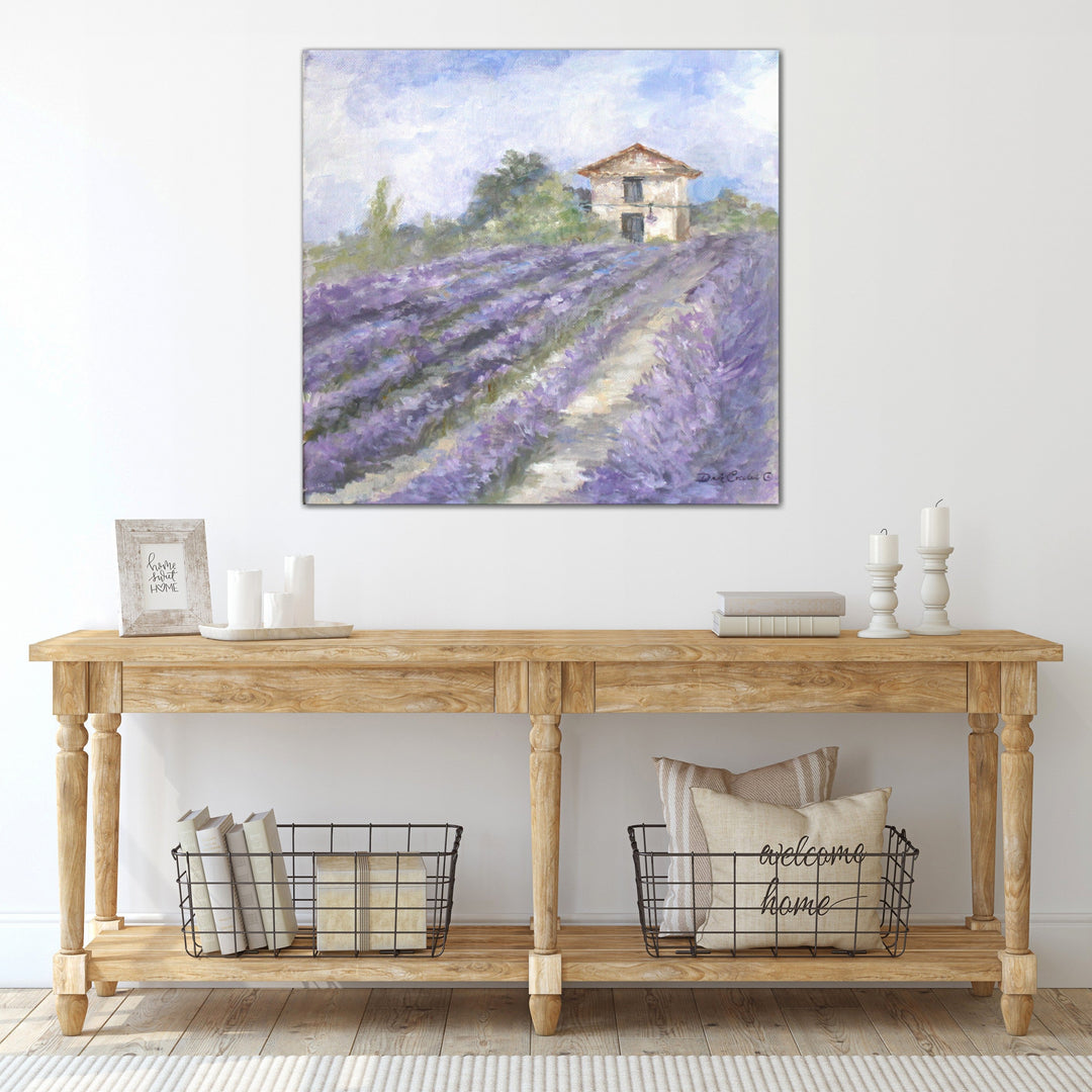 Artwork of a French farmhouse in a lavender field hangs above a wooded entry table with various farmhouse style nic-naks
