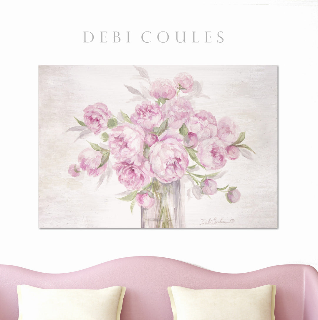 Canvas print of round, pink, peony blooms hanging above a pink sofa.