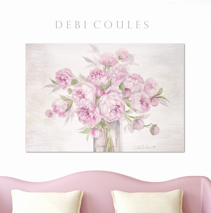 Canvas print of round, pink, peony blooms hanging above a pink sofa.
