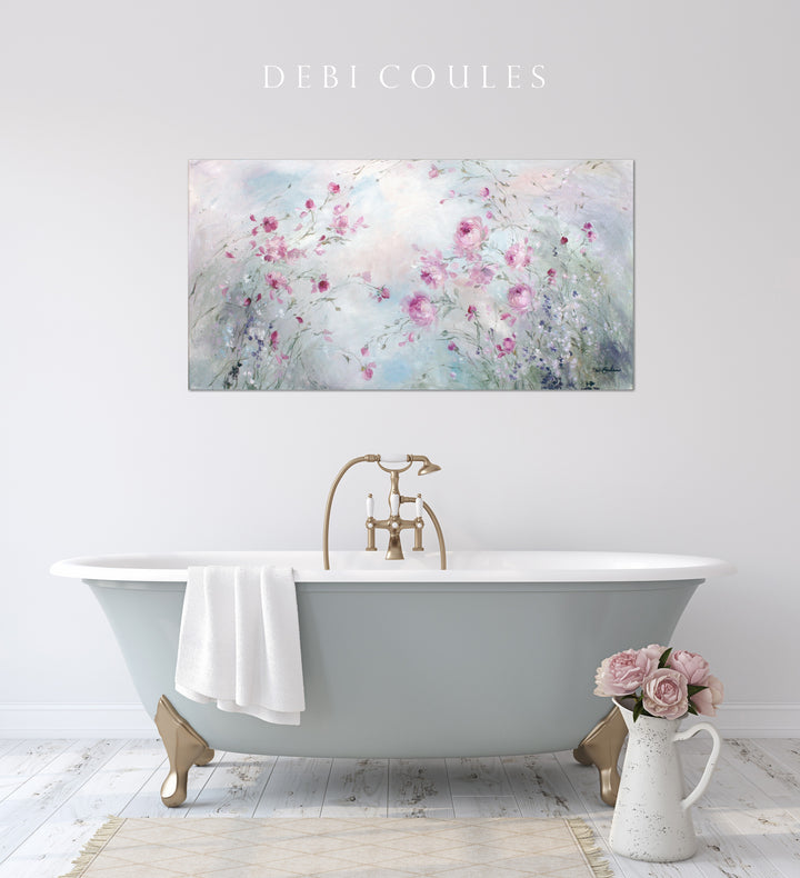 Canvas print of roses in a pale meadow hangs in the bathroom over a freestanding bathtub.