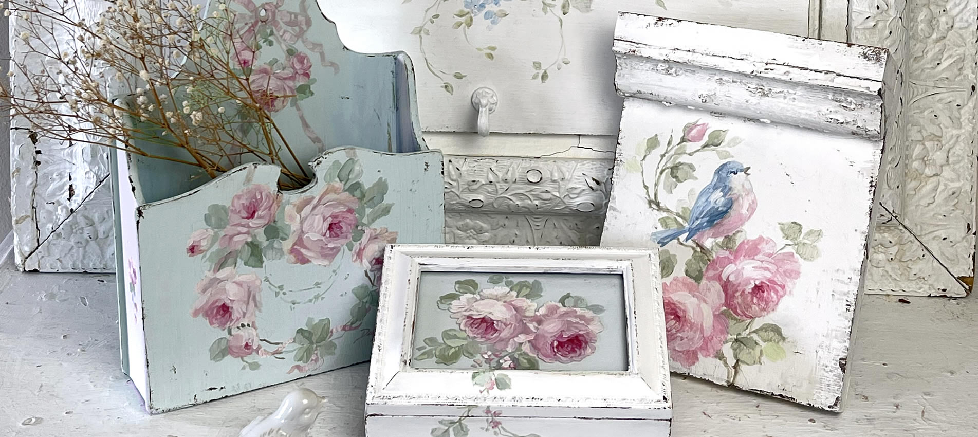 hand-painted cottage-core decor including a rose painted music box, antique plinth blocks, and vintage bluebird coat rack