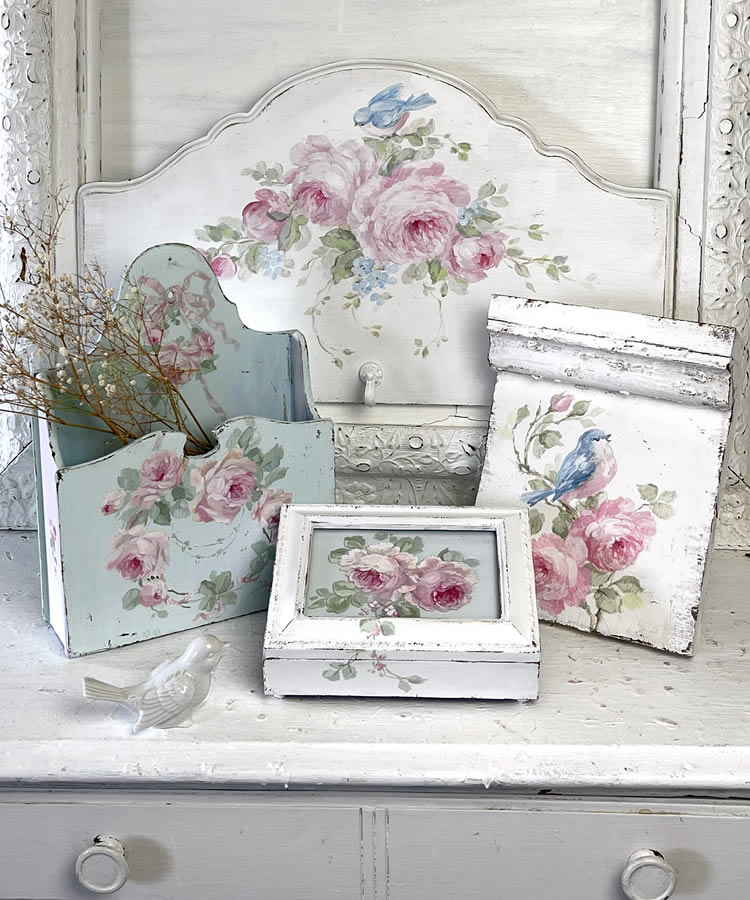 hand-painted cottage-core decor including a rose painted music box, antique plinth blocks, and vintage bluebird coat rack