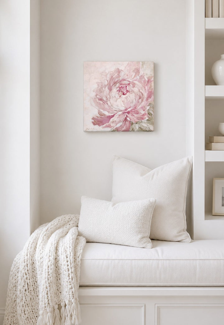 Floral painting above a white bench with pillows and a blanket in a room setting.