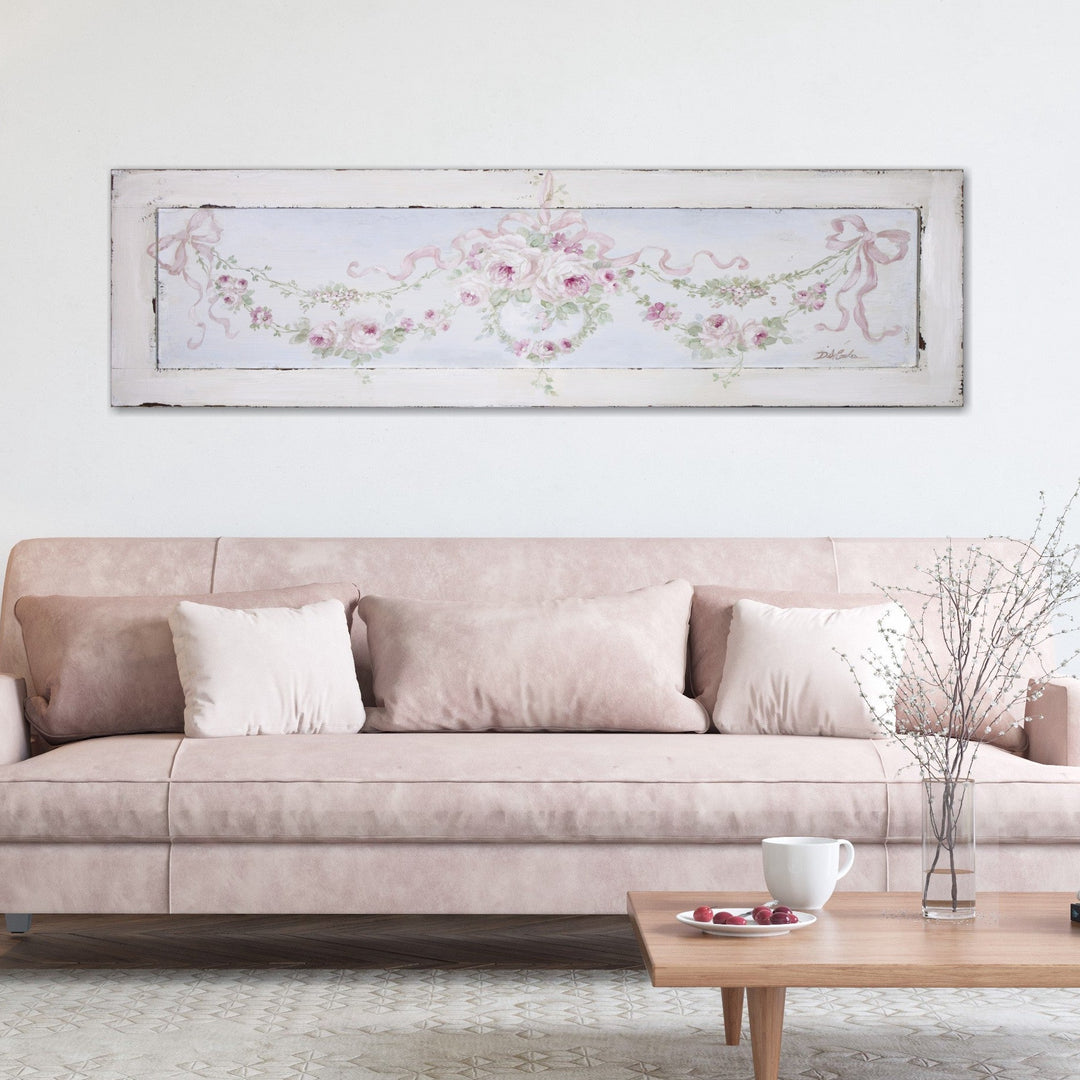 A shabby chic painting of rose garlands hanging above a suede leather couch.