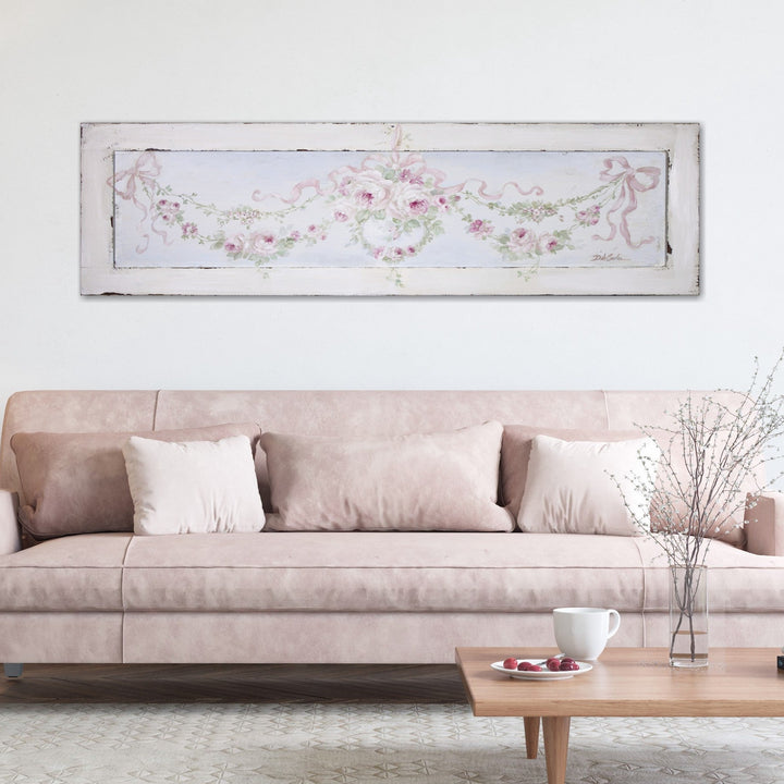 A shabby chic painting of rose garlands hanging above a suede leather couch.