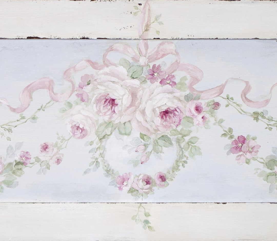 Closeup view of the painting detail of pink roses and ribbons on a white wooden background