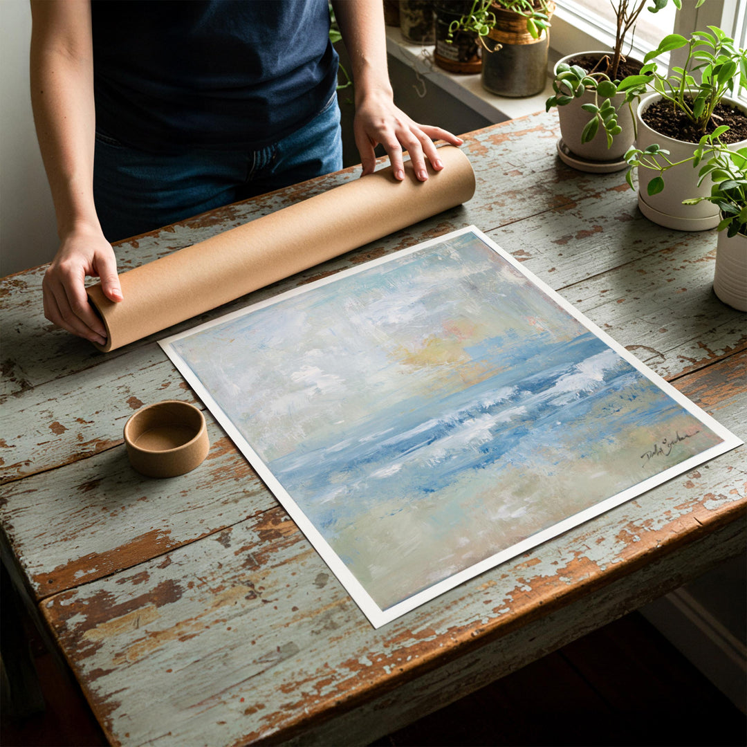 Person rolling up a fine-art paper print of coast artwork of a beachside sunset to be placed in a cardboard mailing tube