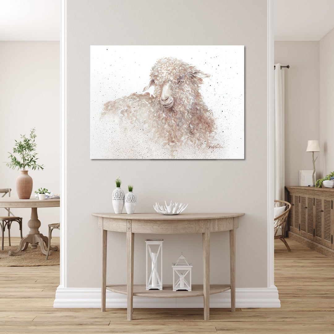 Canvas print of a long-wooled sheep hanging above an entry table in a neutral toned home interior.