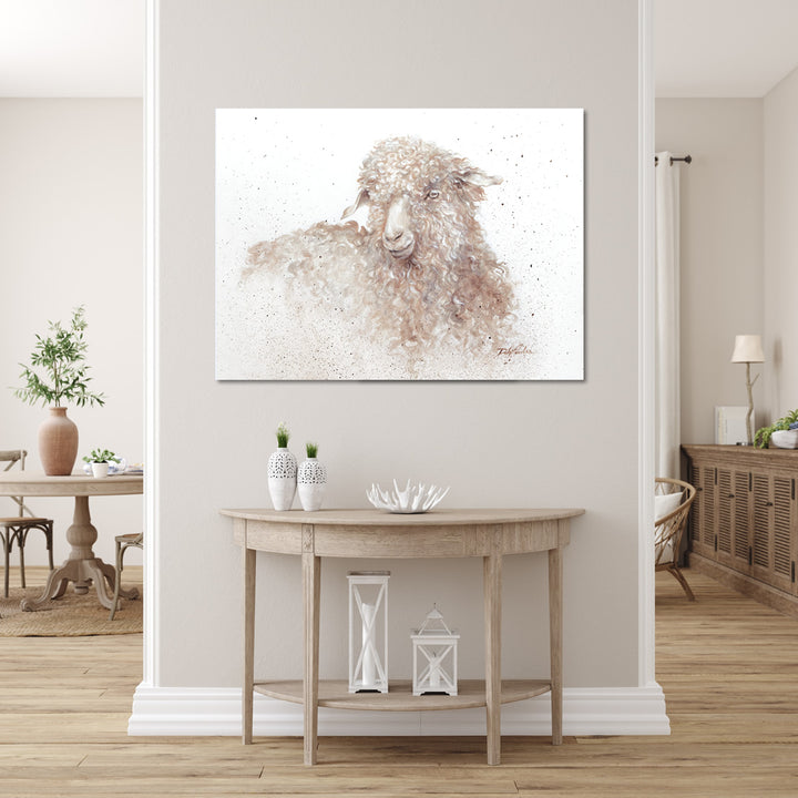 Canvas print of a long-wooled sheep hanging above an entry table in a neutral toned home interior.