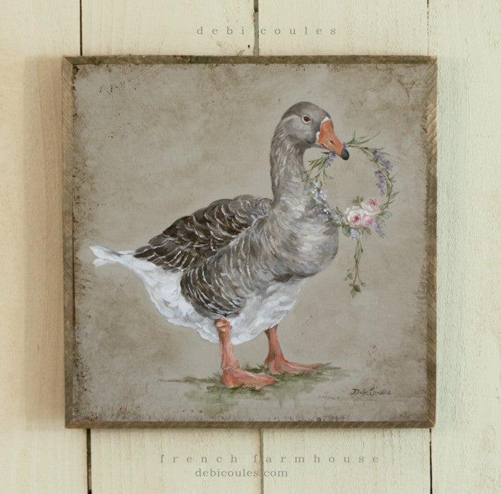 Farmhouse Goose holding a wreath adorned with roses, Pink purple red. Printed on wood and framed in barn wood frame, Debis love for animals is apparent with all her farmhouse collection. Also will add a touch of French Chic to your home décor.