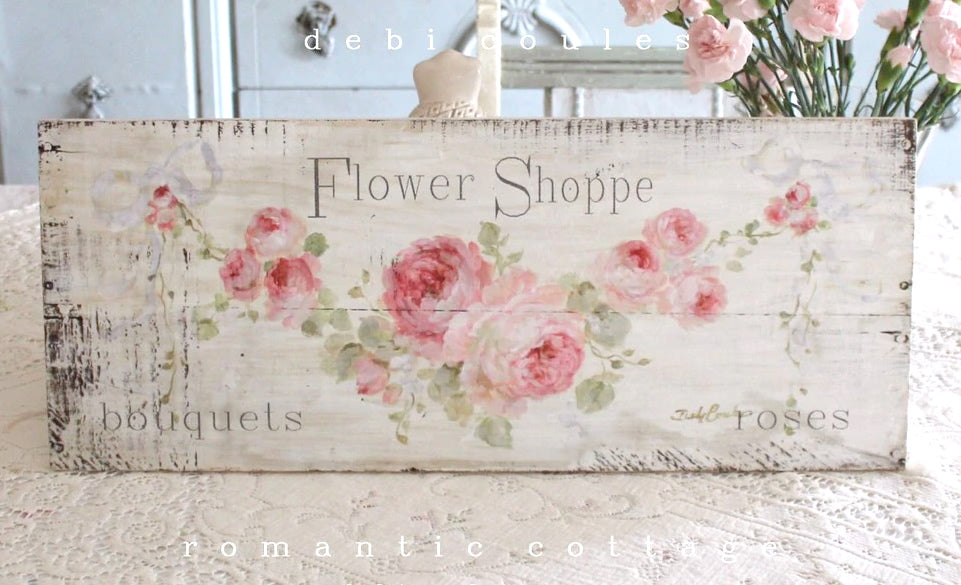 Off white background with lots of distressing. A swag of pink roses with leaves and buds create a wonderful backdrop for the slogan "Flower Shoppe" Perfect for your shabby chic, or french chic 